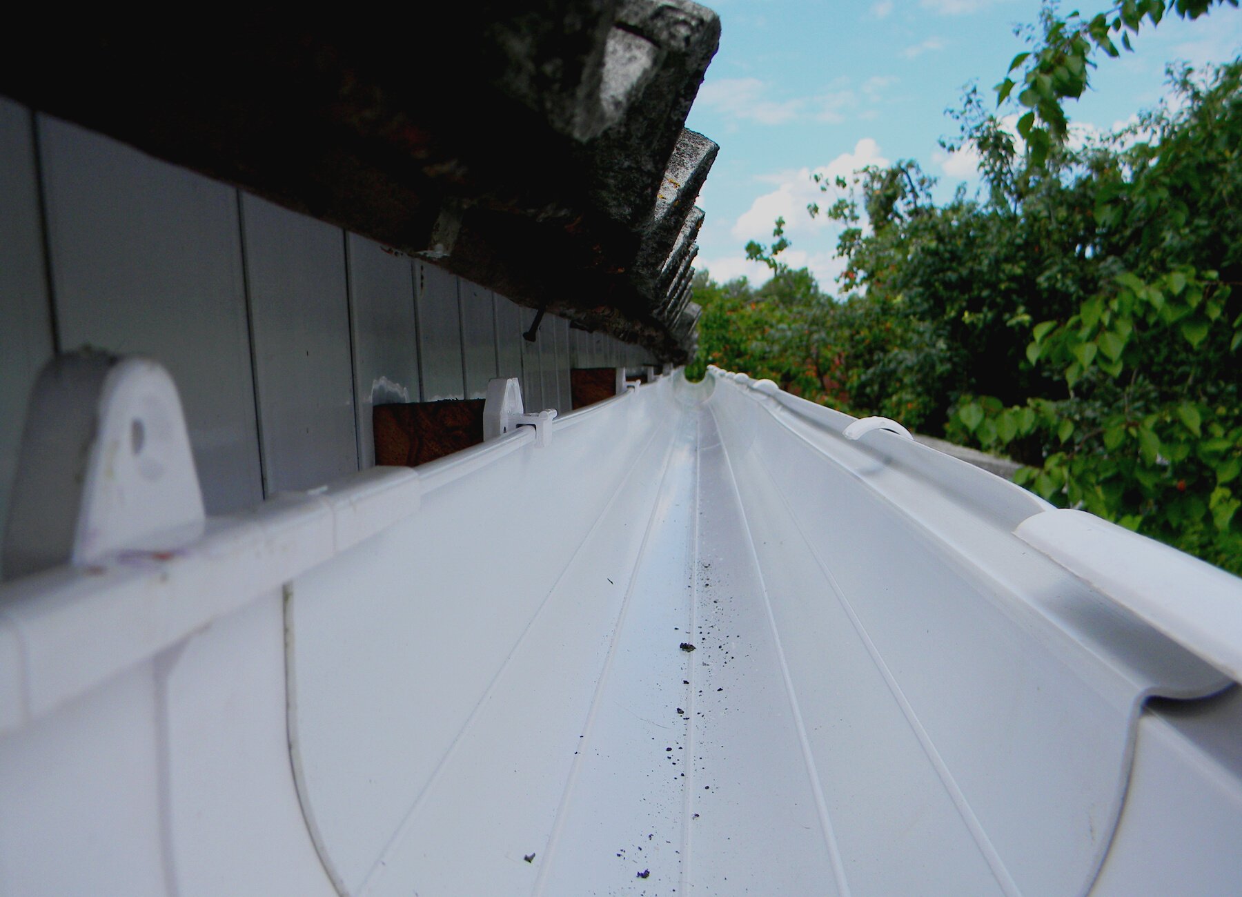 Rain gutter view. Install plastic roof gutter. Guttering repair.