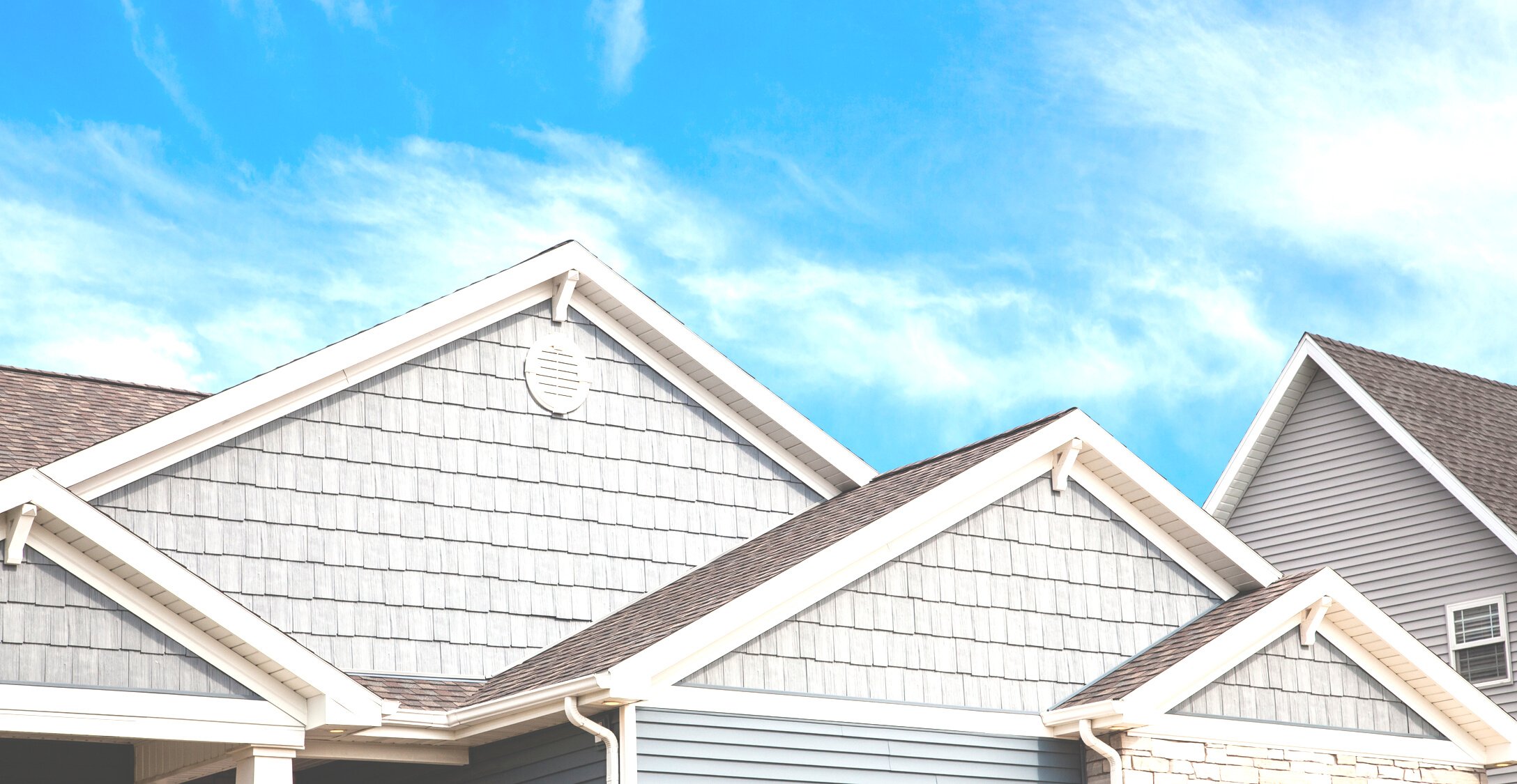 Roof, grey vinyl siding, soffit, gutters on newly built home